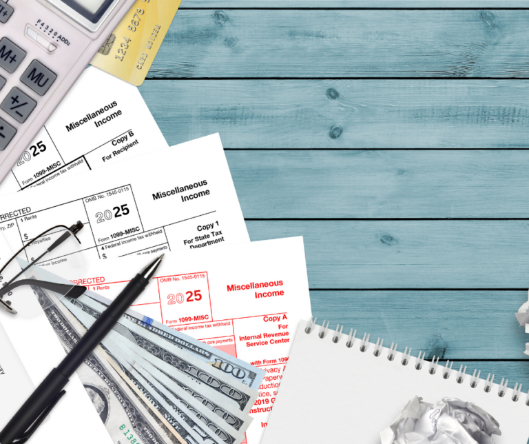 A flat lay of tax documents, a calculator, a pen, U.S. dollar bills, paper clips, a notepad, and crumpled paper on a blue wooden surface, representing tax preparation or financial planning.
